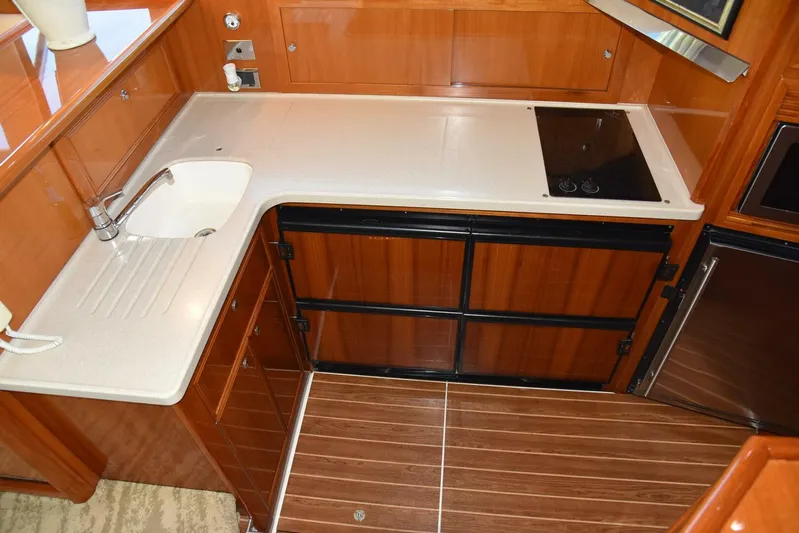 Viviendo El Sueño Yacht Photos Pics 2005 Riviera 51 yacht kitchen with wooden cabinets, sink, and stovetop.