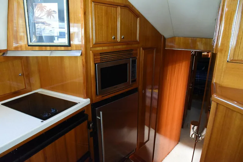 Viviendo El Sueño Yacht Photos Pics 2005 Riviera 51 yacht interior with wooden cabinetry, microwave, and compact kitchen area.