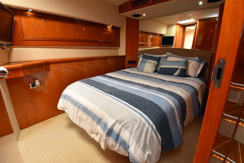 Viviendo El Sueño Yacht Photos Pics Luxurious bedroom interior of 2005 Riviera 51 yacht with striped bedding and wooden accents.