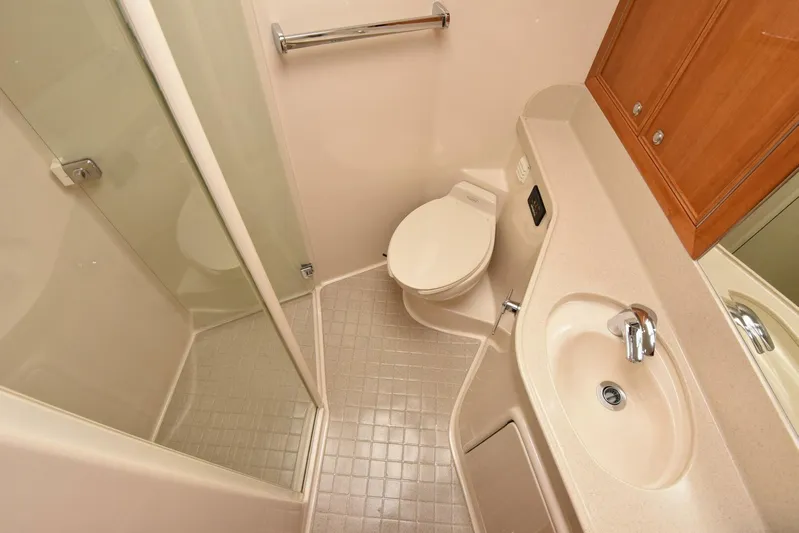 Viviendo El Sueño Yacht Photos Pics Compact bathroom in a 2005 Riviera 51 yacht, featuring a shower, toilet, and sink.