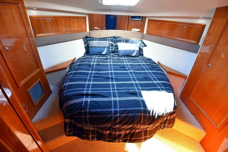 Viviendo El Sueño Yacht Photos Pics Luxurious bedroom interior of 2005 Riviera 51 yacht with plaid bedding and wooden cabinetry.