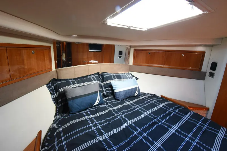 Viviendo El Sueño Yacht Photos Pics Luxurious bedroom interior of a 2005 Riviera 51 yacht with plaid bedding and wooden cabinets.