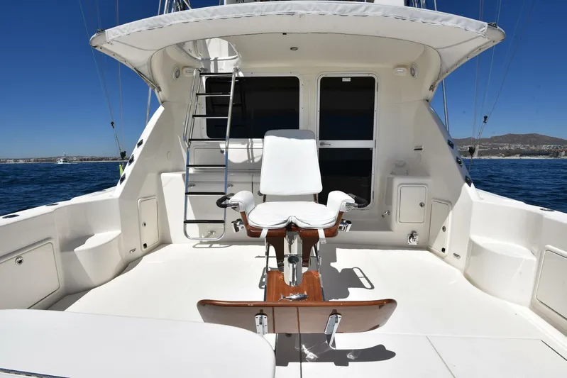 Viviendo El Sueño Yacht Photos Pics 2005 Riviera 51 yacht deck with fishing chair and ladder, set against a clear blue sky.