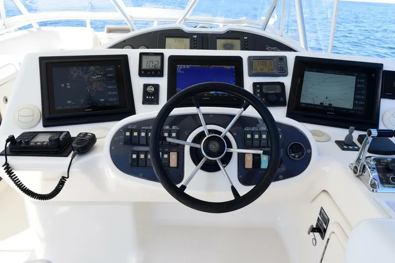 Viviendo El Sueño Yacht Photos Pics Control panel of a 2005 Riviera 51 yacht with navigation screens and steering wheel.