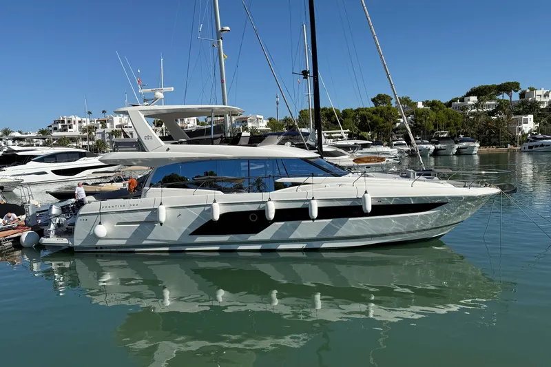  Yacht Photos Pics 2024 Prestige 590 yacht docked in a marina, surrounded by other luxury boats.