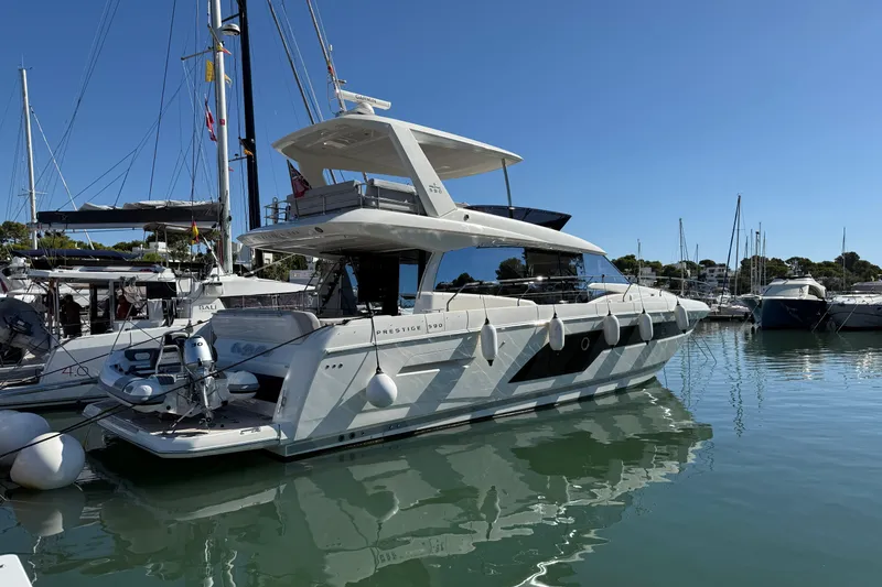  Yacht Photos Pics 2024 Prestige 590 yacht docked in a marina under clear blue skies.