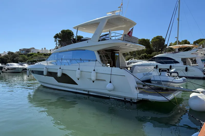  Yacht Photos Pics 2024 Prestige 590 yacht docked in a serene marina under clear blue skies.