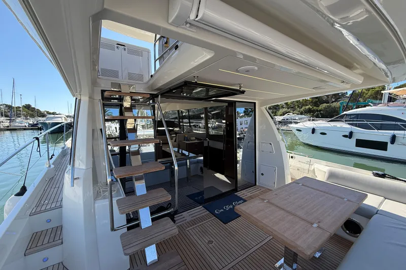  Yacht Photos Pics 2024 Prestige 590 yacht interior with wooden stairs, table, and marina view.