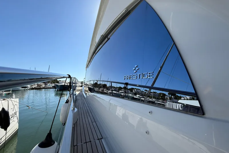  Yacht Photos Pics 2024 Prestige 590 yacht reflecting marina view, sleek design, sunny day.