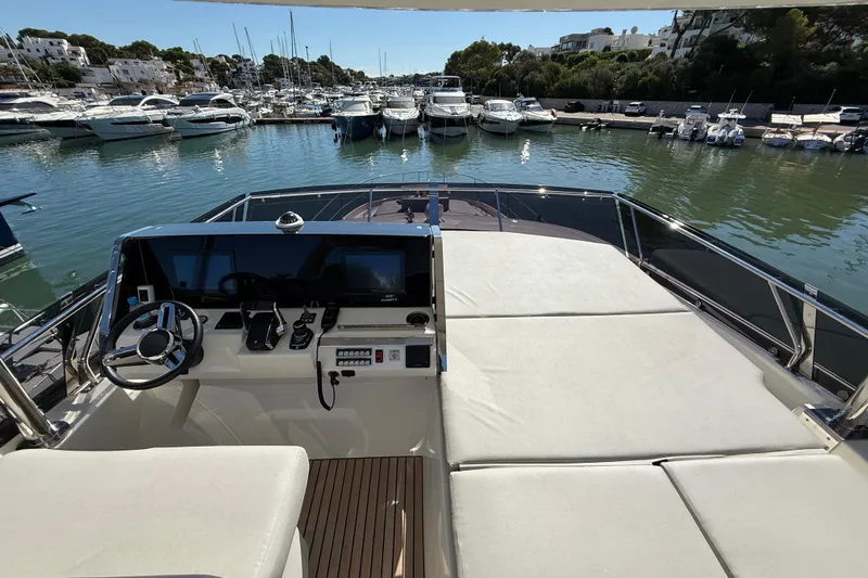  Yacht Photos Pics 2024 Prestige 590 yacht helm and deck, docked in a marina with other boats.