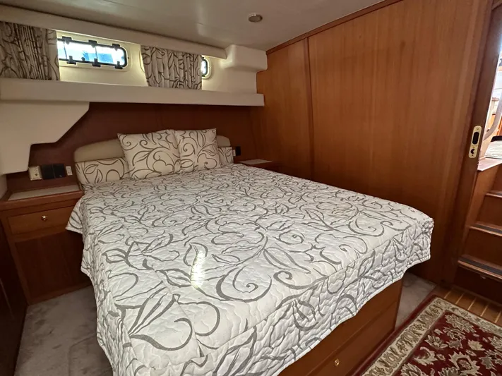  Yacht Photos Pics Aft cabin bedroom in 2000 Mainship 43 Trawler with elegant bedding and wooden interior.