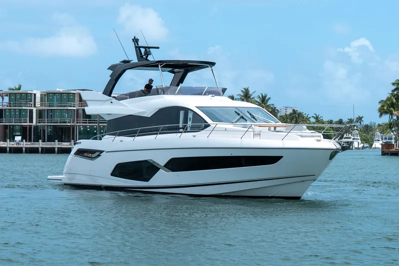  Yacht Photos Pics 2024 Sunseeker Manhattan 68 yacht cruising on a sunny day, with modern architecture in the background.