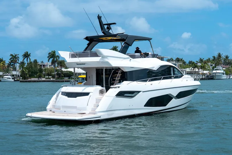  Yacht Photos Pics 2024 Sunseeker Manhattan 68 yacht cruising on a sunny day, surrounded by palm trees.