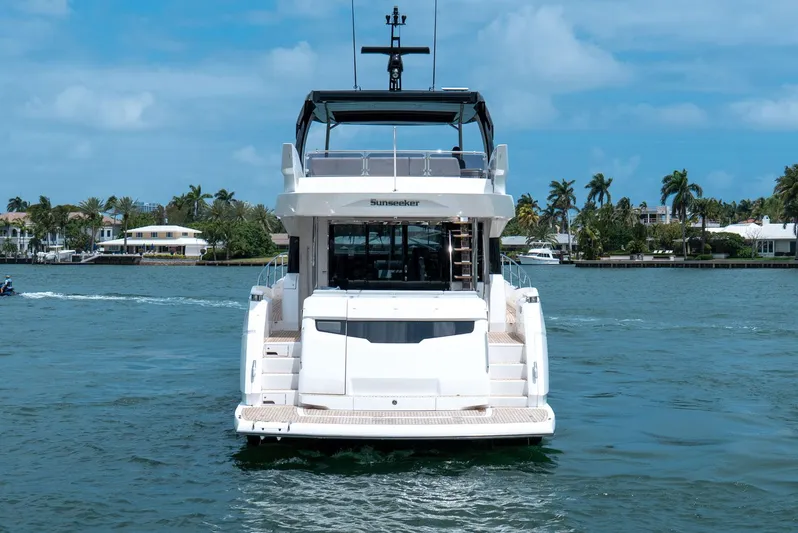 Yacht Photos Pics 2024 Sunseeker Manhattan 68 yacht on water, rear view, with tropical backdrop.