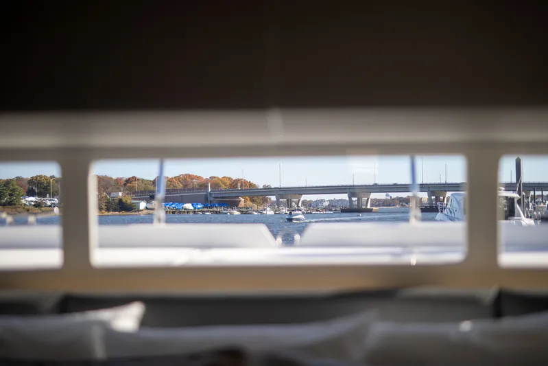  Yacht Photos Pics View from Aquila 54 Yacht window, showcasing a bridge and waterfront scenery, 2023.