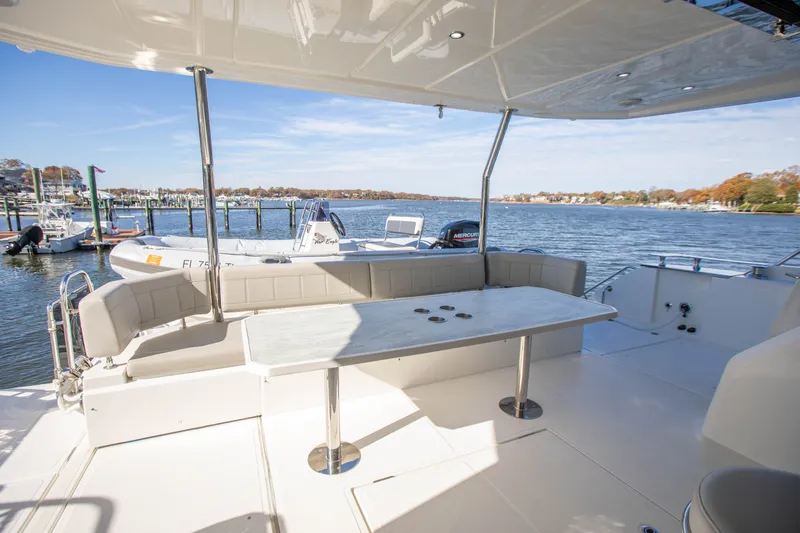  Yacht Photos Pics 2023 Aquila 54 Yacht deck with seating, table, and scenic waterfront view.