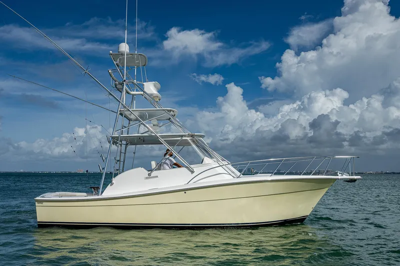  Yacht Photos Pics 2006 Topaz 32 Express boat on calm waters under a blue sky with clouds.