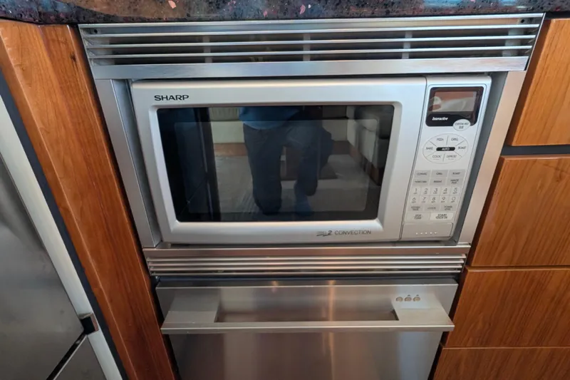 Casa Amigos Yacht Photos Pics Sharp microwave in a 2010 Fairline Squadron yacht kitchen, surrounded by wooden cabinetry.