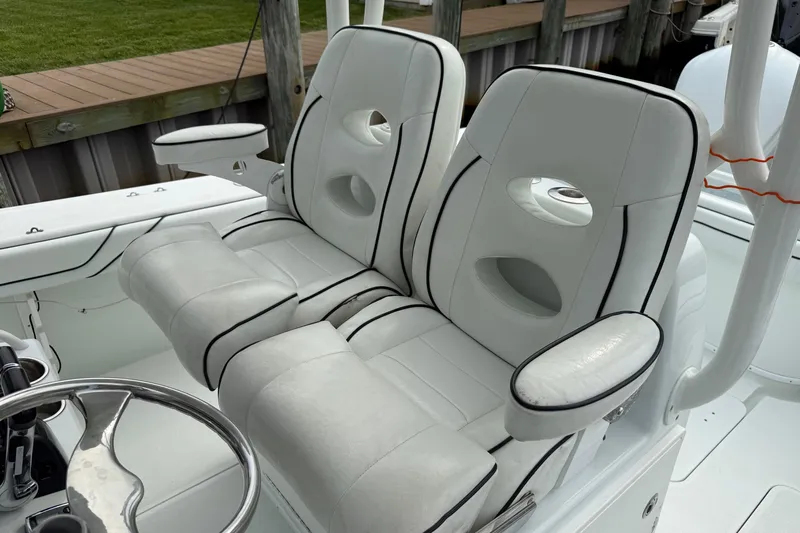  Yacht Photos Pics 2015 Yellowfin 32 boat with white cushioned seats and steering wheel, docked by wooden pier.