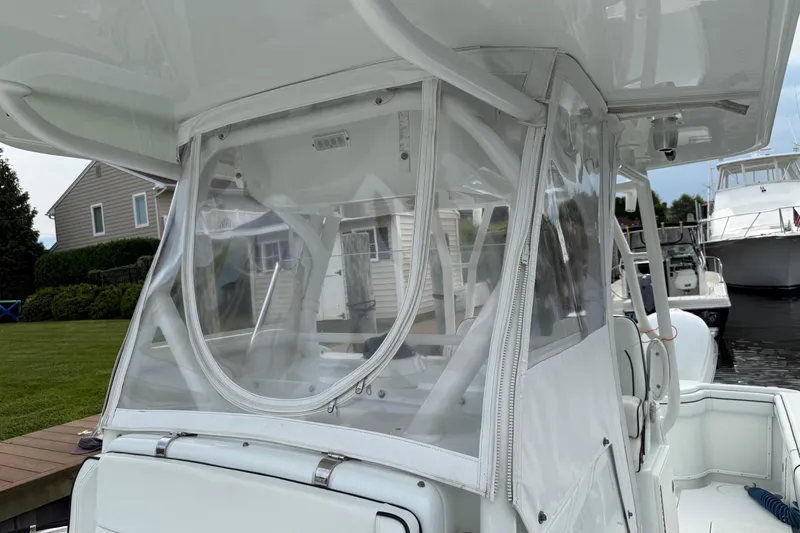  Yacht Photos Pics 2015 Yellowfin 32 boat with clear protective enclosure, docked near houses and other boats.