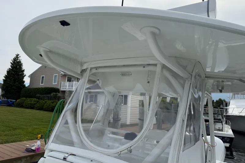  Yacht Photos Pics 2015 Yellowfin 32 boat with clear enclosure and white hardtop, docked near a house.