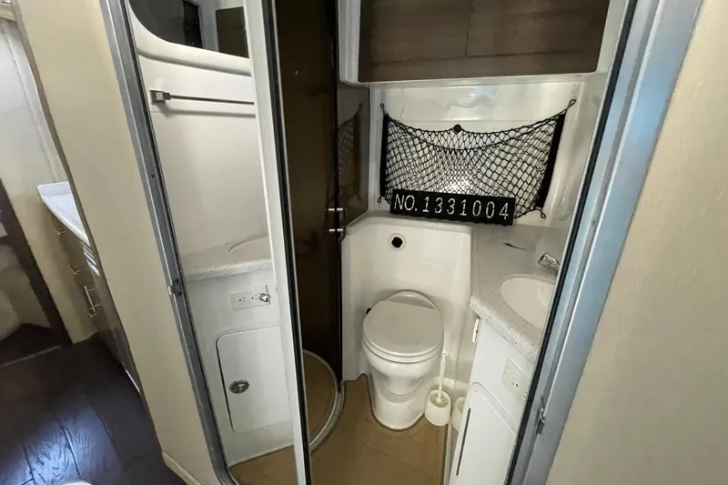  Yacht Photos Pics 2019 Rinker 370 EX boat bathroom with toilet, sink, and storage net.