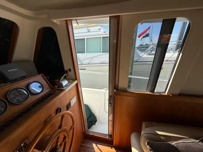 Real Therapy Yacht Photos Pics Interior view of 2001 Mainship 390 Trawler with wooden helm and gauges, open door to deck.