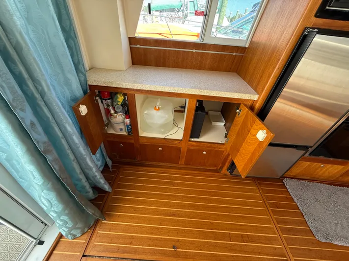Real Therapy Yacht Photos Pics 2001 Mainship 390 Trawler interior with open cabinets, wooden flooring, and countertop.