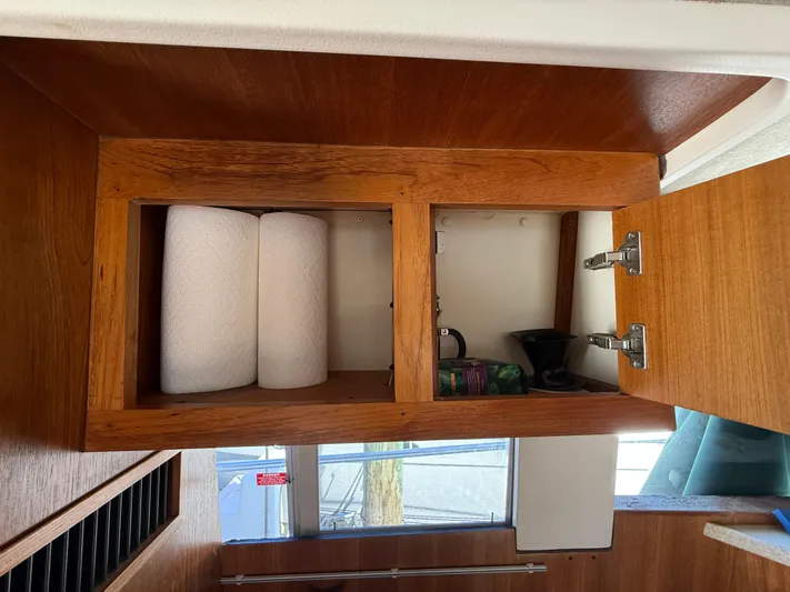 Real Therapy Yacht Photos Pics Wooden cabinet interior on a 2001 Mainship 390 Trawler, storing paper towels and miscellaneous items.