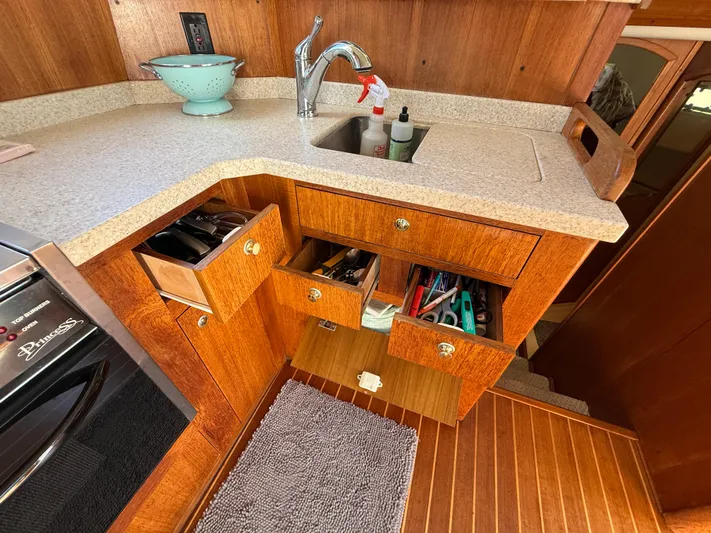 Real Therapy Yacht Photos Pics 2001 Mainship 390 Trawler kitchen with wooden cabinets, open drawers, and countertop sink.