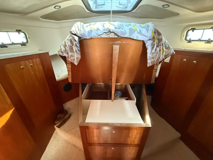Real Therapy Yacht Photos Pics 2001 Mainship 390 Trawler cabin with raised bed and wooden storage drawers.