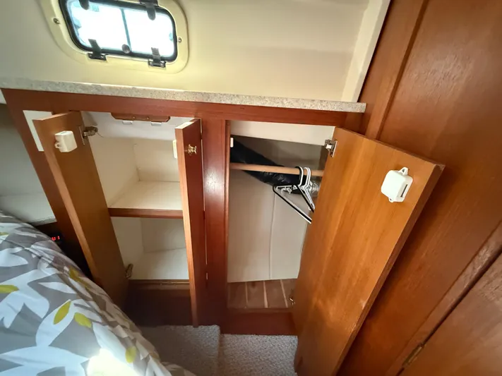 Real Therapy Yacht Photos Pics 2001 Mainship 390 Trawler cabin closet with open wooden doors and hangers.