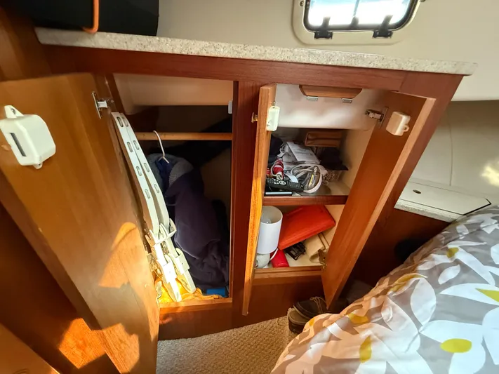 Real Therapy Yacht Photos Pics 2001 Mainship 390 Trawler cabin storage with open wooden cabinets and various items inside.