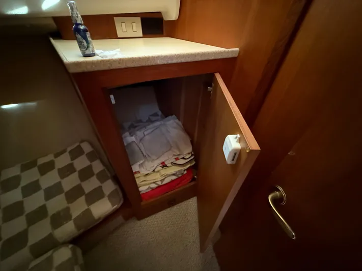 Real Therapy Yacht Photos Pics 2001 Mainship 390 Trawler interior with open cabinet, folded linens, and checkered cushion.