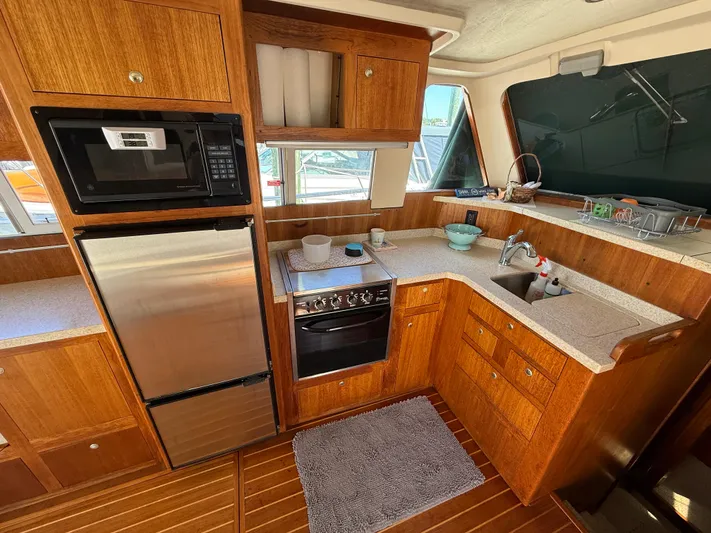 Real Therapy Yacht Photos Pics 2001 Mainship 390 Trawler kitchen with wood cabinetry, stainless steel appliances, and corner sink.