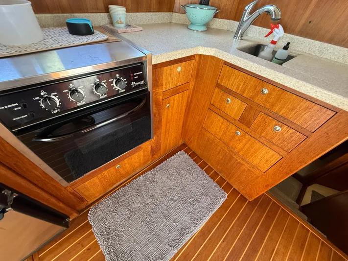 Real Therapy Yacht Photos Pics 2001 Mainship 390 Trawler kitchen with stove, wooden cabinets, and sink.