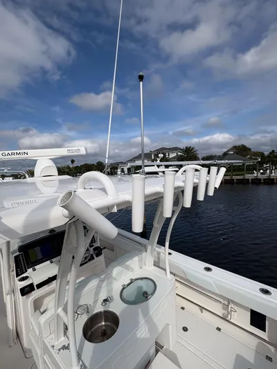  Yacht Photos Pics 2018 Robalo R302 Center Console boat with fishing rod holders, docked under a partly cloudy sky.
