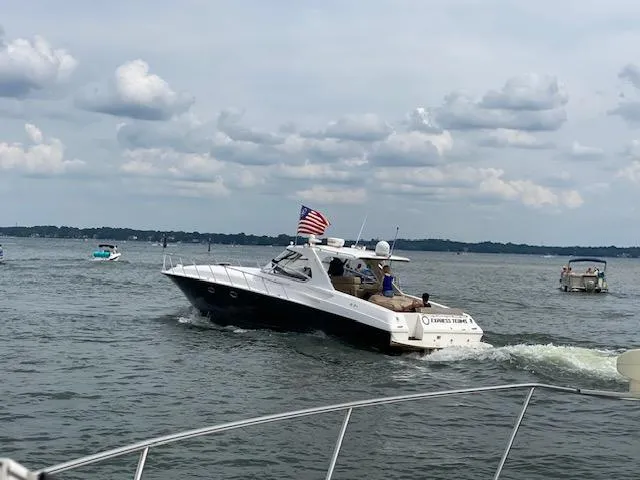 Yacht Photos Pics 2009 Fountain 48 Express Cruiser on a lake, American flag waving, cloudy sky.