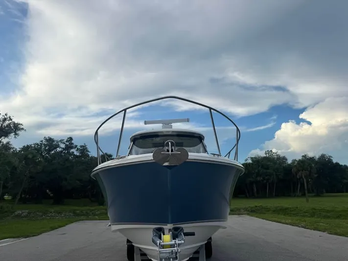  Yacht Photos Pics 2023 Boston Whaler 325 Conquest boat on trailer under cloudy sky.