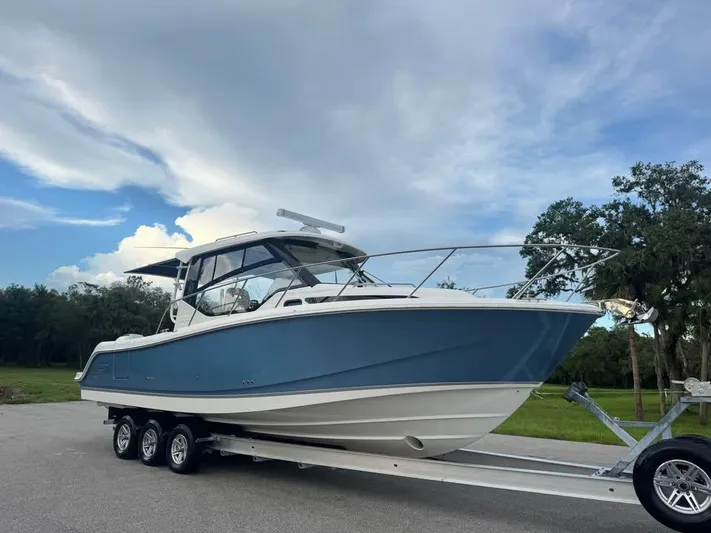  Yacht Photos Pics 2023 Boston Whaler 325 Conquest boat on trailer, parked outdoors under a cloudy sky.