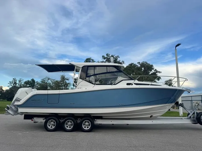  Yacht Photos Pics 2023 Boston Whaler 325 Conquest boat on a trailer, under a clear sky.