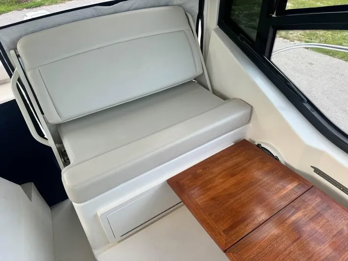  Yacht Photos Pics 2023 Boston Whaler 325 Conquest interior with cushioned seating and wooden table.