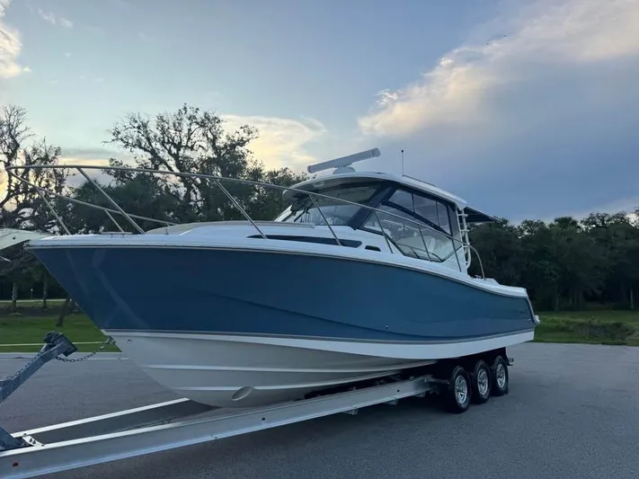  Yacht Photos Pics 2023 Boston Whaler 325 Conquest boat on trailer at sunset, side view.