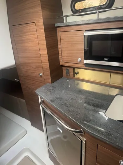  Yacht Photos Pics 2023 Boston Whaler 325 Conquest interior with modern kitchenette and wood finish.