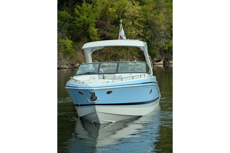 310 Bow Rider Yacht Photos Pics 2025 Formula 310 Bowrider I/O boat on calm water, surrounded by lush greenery.