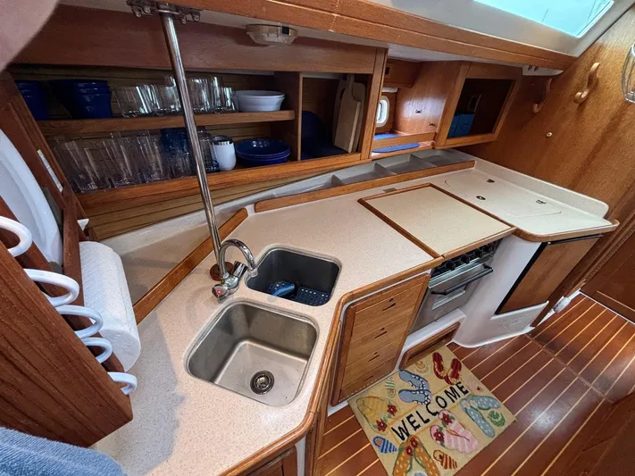 Unbridled Yacht Photos Pics 1996 Catalina 42 yacht kitchen with dual sinks, wooden cabinetry, and welcome mat.
