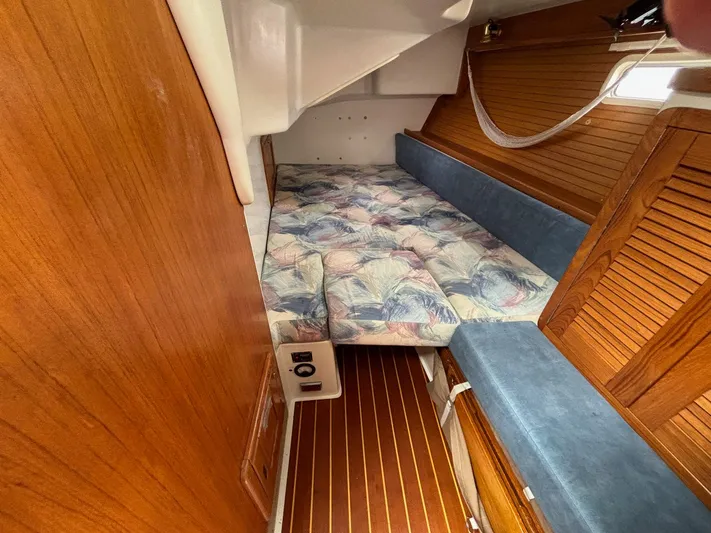 Unbridled Yacht Photos Pics Cozy cabin interior of a 1996 Catalina 42 sailboat with wood paneling and patterned bedding.