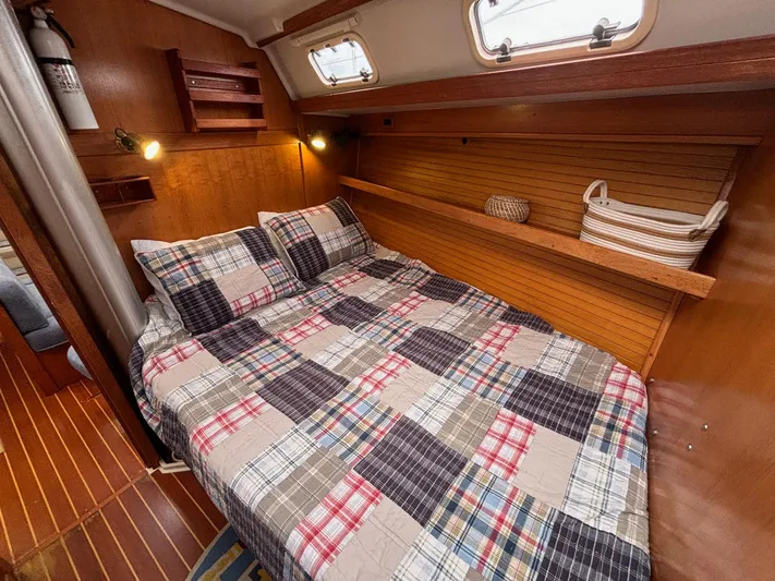Unbridled Yacht Photos Pics Cozy cabin interior of 1996 Catalina 42 sailboat with plaid bedding and wooden accents.