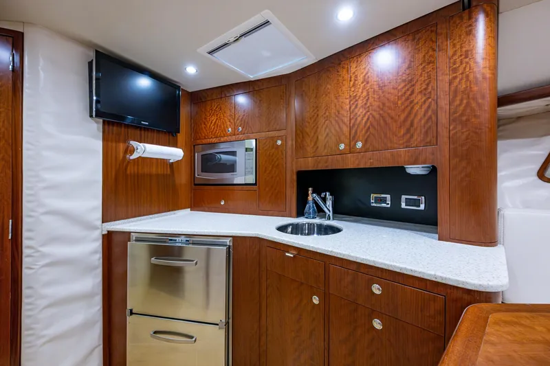 Refit 2018 - Reel Deal Yacht Photos Pics Luxurious 2012 SeaVee 43 Express yacht kitchen with wood cabinetry and modern appliances.