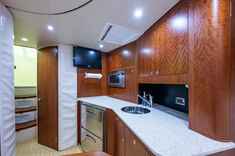Refit 2018 - Reel Deal Yacht Photos Pics Luxurious 2012 SeaVee 43 Express yacht interior with modern kitchen and wood cabinetry.
